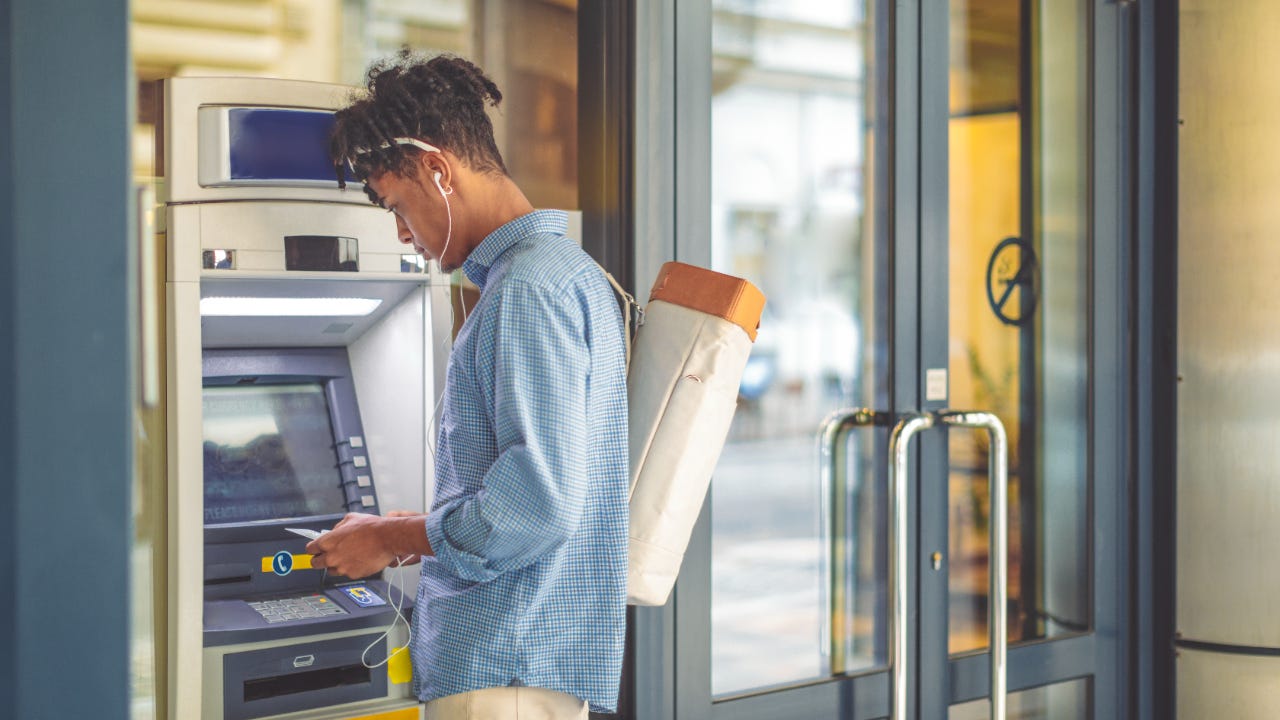 Young man getting cash out of ATM