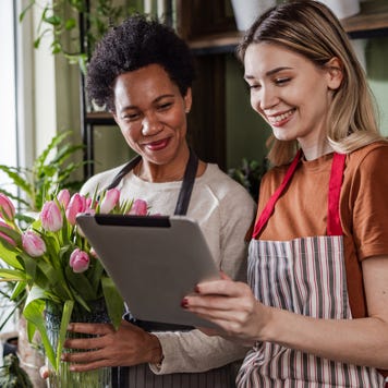 Two women using digital tablet in their flower workshop