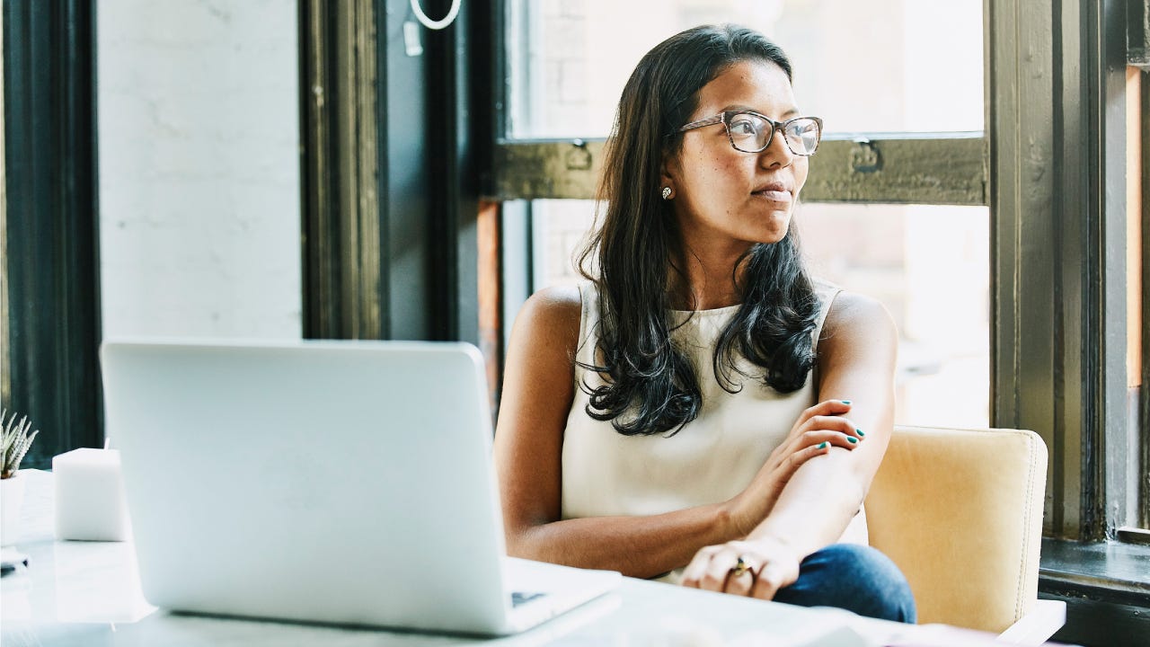 Businesswoman looking out window while seated at desk in office