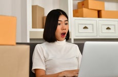 Shocked young woman looking at laptop