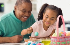 Grandfather and granddaughter decorate Easter eggs together