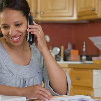 Middle-aged woman on phone and looking at laptop