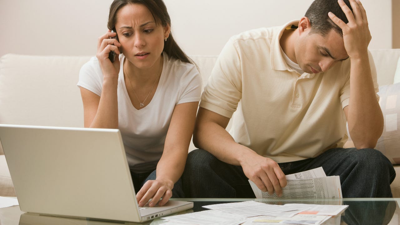 Distressed couple looking at documents and laptop