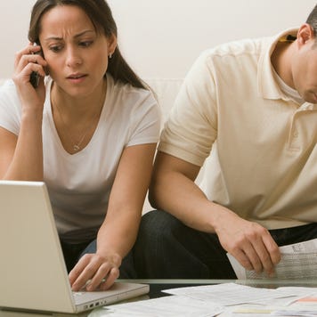 Distressed couple looking at documents and laptop