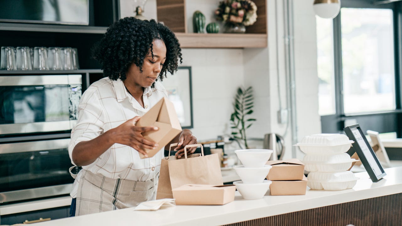 A restaurant owner packages food for take out.