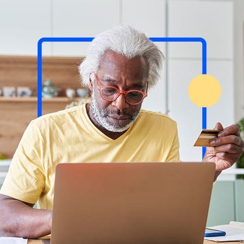 Man using laptop with credit card in hand
