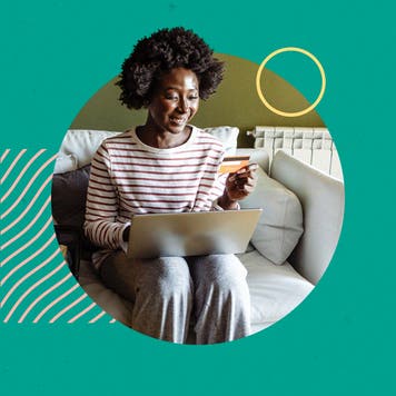 Woman sitting on couch with laptop with credit card in hand