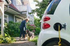 Woman walking to entrance of her house while her electric car is charging