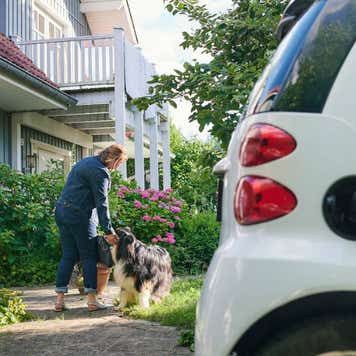 Woman walking to entrance of her house while her electric car is charging