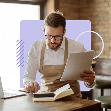 A business owner in an apron looks over paperwork