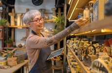 artist woman using digital tablet for stock counting on pottery shop