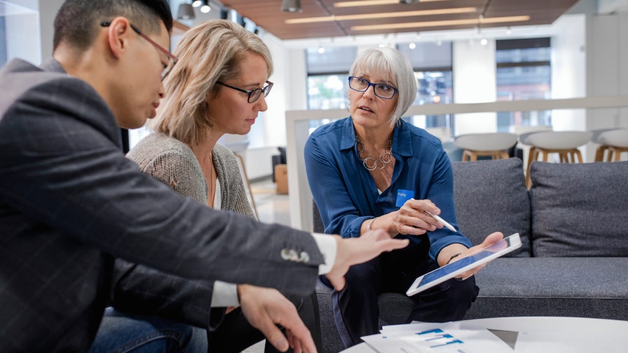 Loan manager with digital tablet meeting with couple in bank