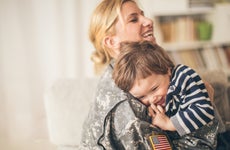Photo of smiling young woman soldier and her son seeing after a long time and enjoying in their living room.