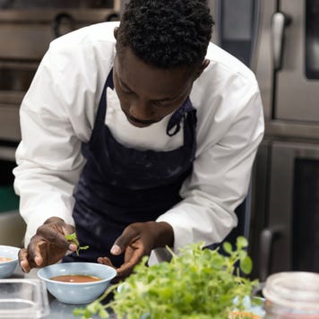 Chef garnishing soup in restaurant kitchen