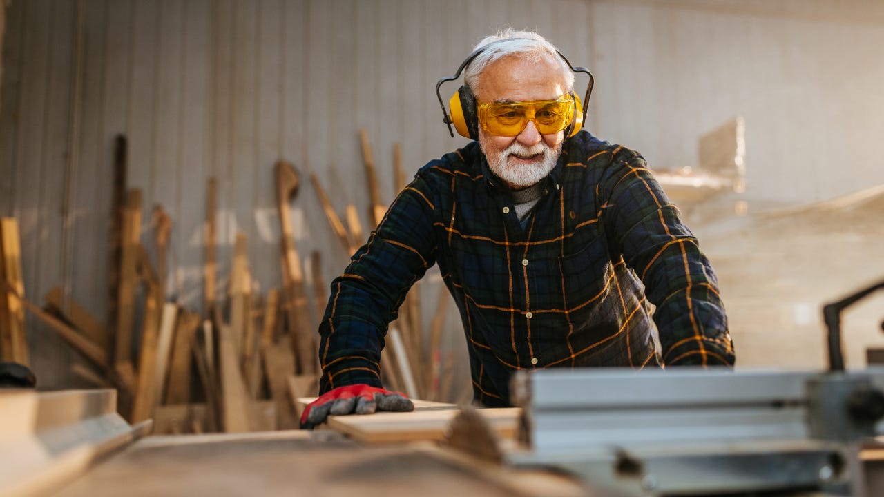 A carpenter uses a table saw in his workshop.