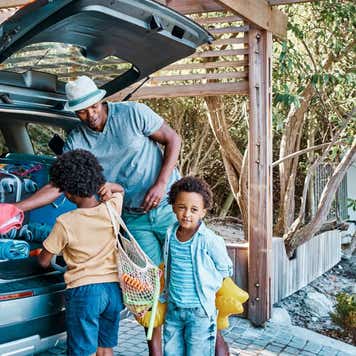 Father packing luggage in a car preparing to travel to the beach with his kids