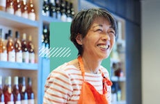 A shop owner wearing an apron smiles.