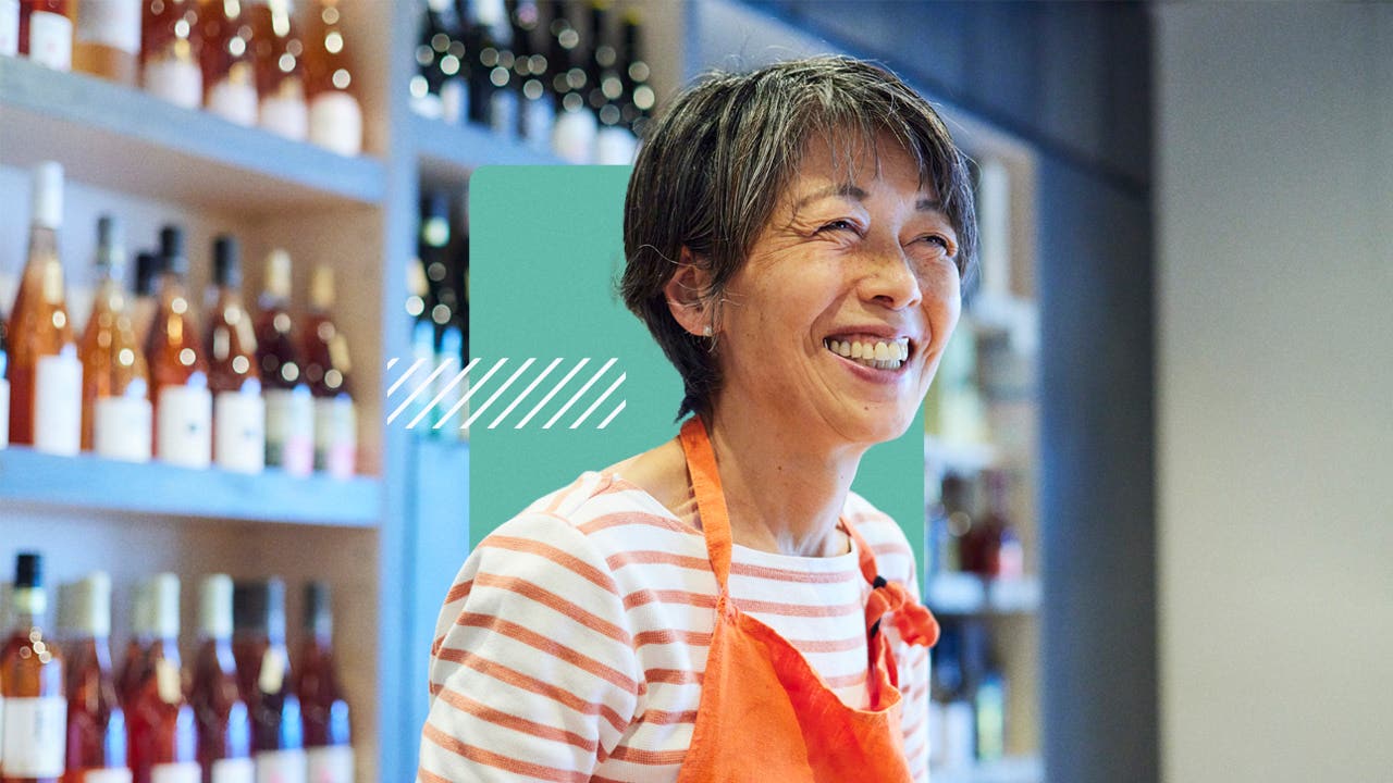 A shop owner wearing an apron smiles.