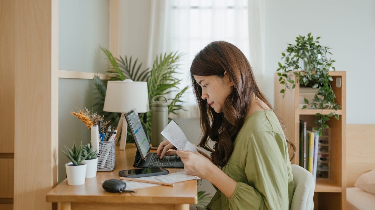 Woman holding paper various expense bills and plans for personal finances at her home.