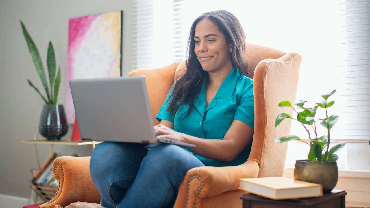 Woman in armchair at home using a laptop
