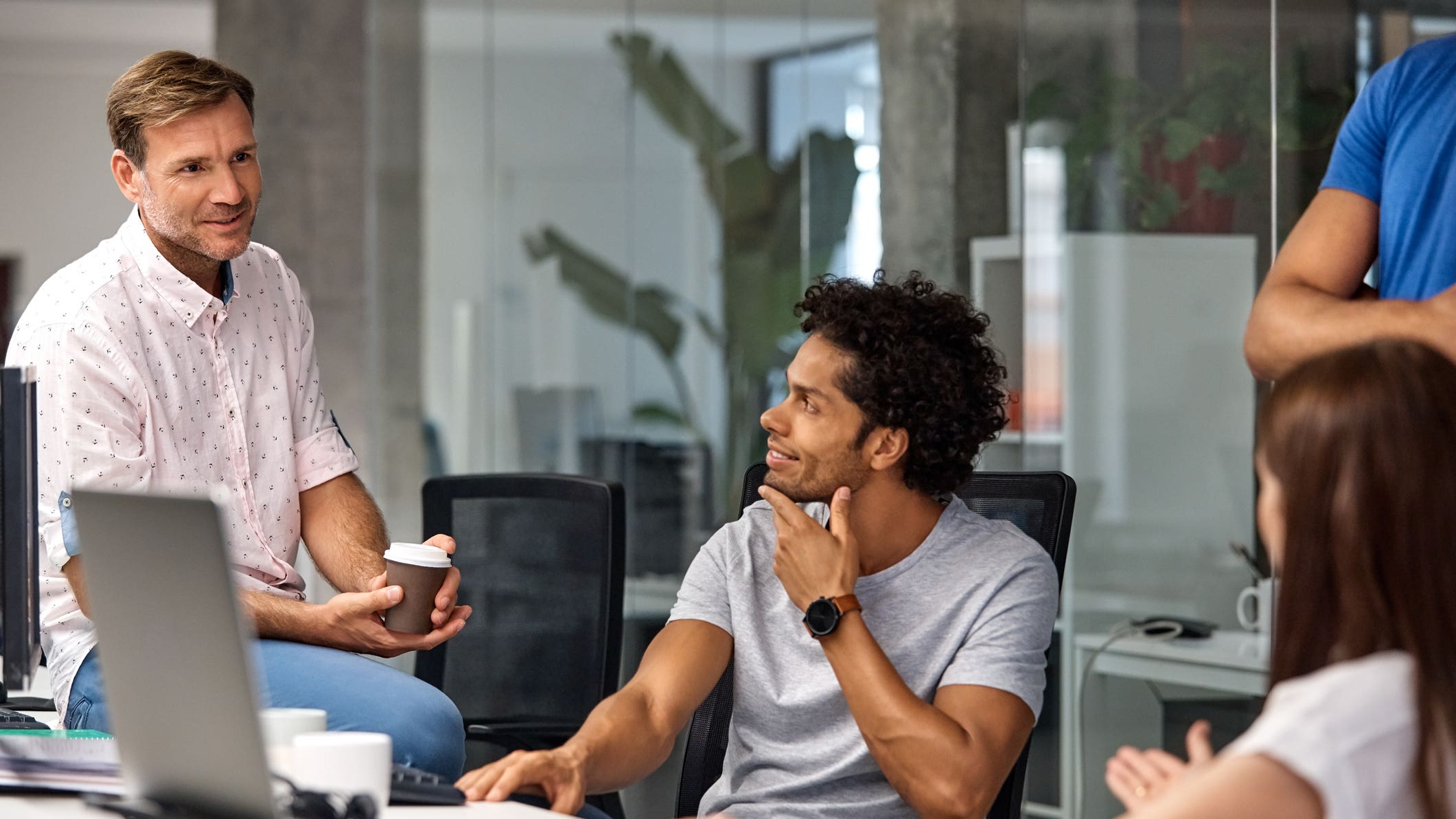 Coworkers listening to mature businessman in the office.