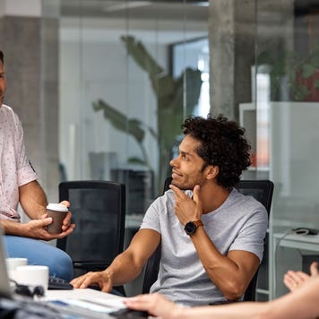 Coworkers listening to mature businessman in the office.