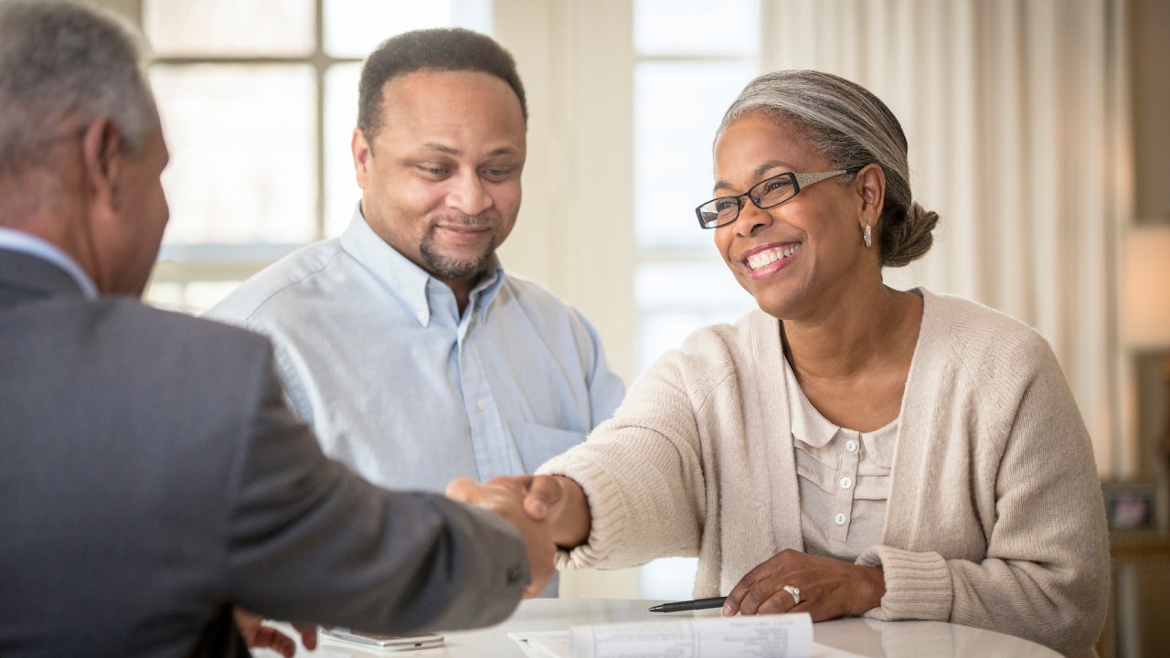 Couple shaking hands with businessman