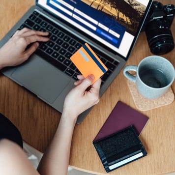 High angle view of young woman booking flight tickets online using laptop