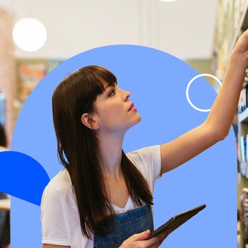 Woman holding a tablet reaches up to a shelf.