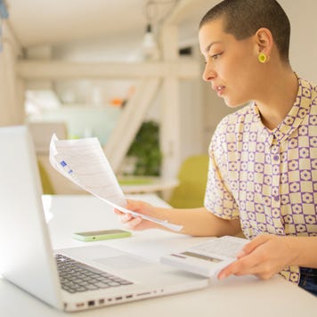 Business owner looking over documents in front of a laptop