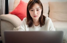 Young Asian woman using laptop , sitting at living home.