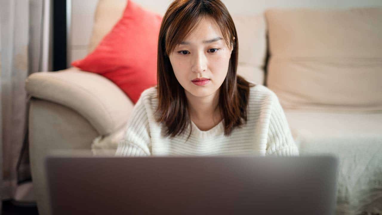 Young Asian woman using laptop , sitting at living home.