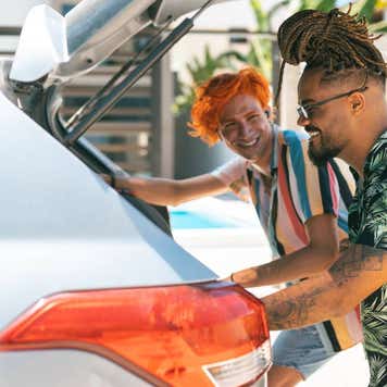 Friends picking up luggage from the trunk of the car