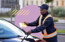 An officer slipping a parking ticket under a car's windshield.