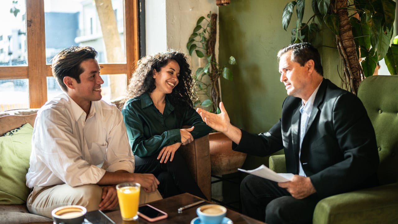 Mid adult couple having a meeting with a financial advisor at a coffee shop