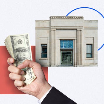 Hand holding cash and a bank building in the background