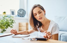 Young woman preparing home budget, using laptop and calculator