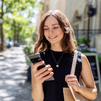 Smiling person with smartphone walking on the street