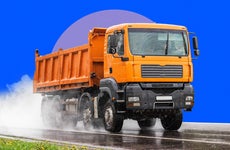 A dump truck is driven along a wet stretch of road.