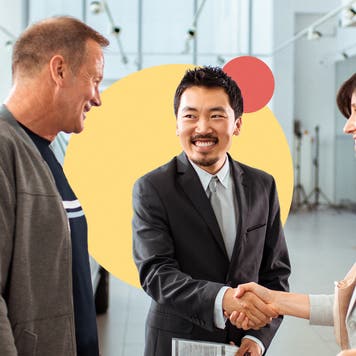 A couple at a car dealership shaking hands after settling on an offer.