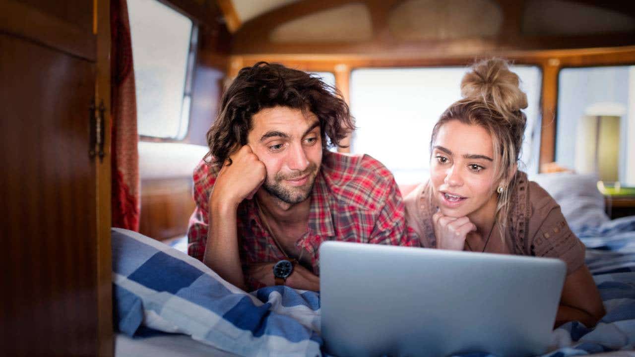 Surprised couple watching on laptop in campervan
