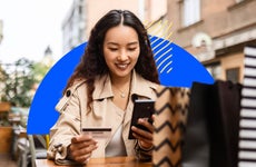 design element of a women smiling while holding a cellphone and credit card in her hands