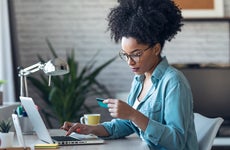 Pretty young afro woman shopping online with credit card with laptop while working on office at home.