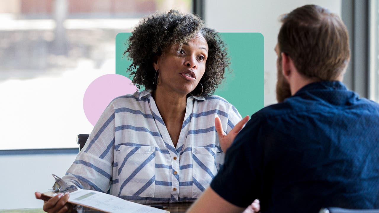 A client speaking with a consultant on an insurance policy. They are in an office with design elements (solid shapes) in the background.