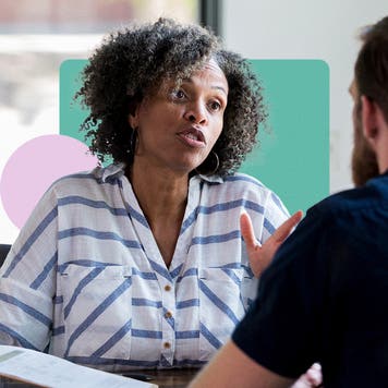 A client speaking with a consultant on an insurance policy. They are in an office with design elements (solid shapes) in the background.