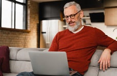 Man sitting on couch and reading laptop