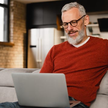 Man sitting on couch and reading laptop
