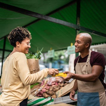 Young woman paying with mobile phone at a street market