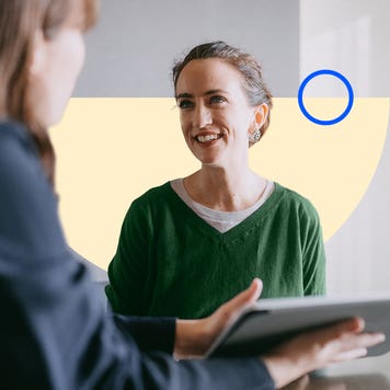 Two people speaking while holding a tablet.