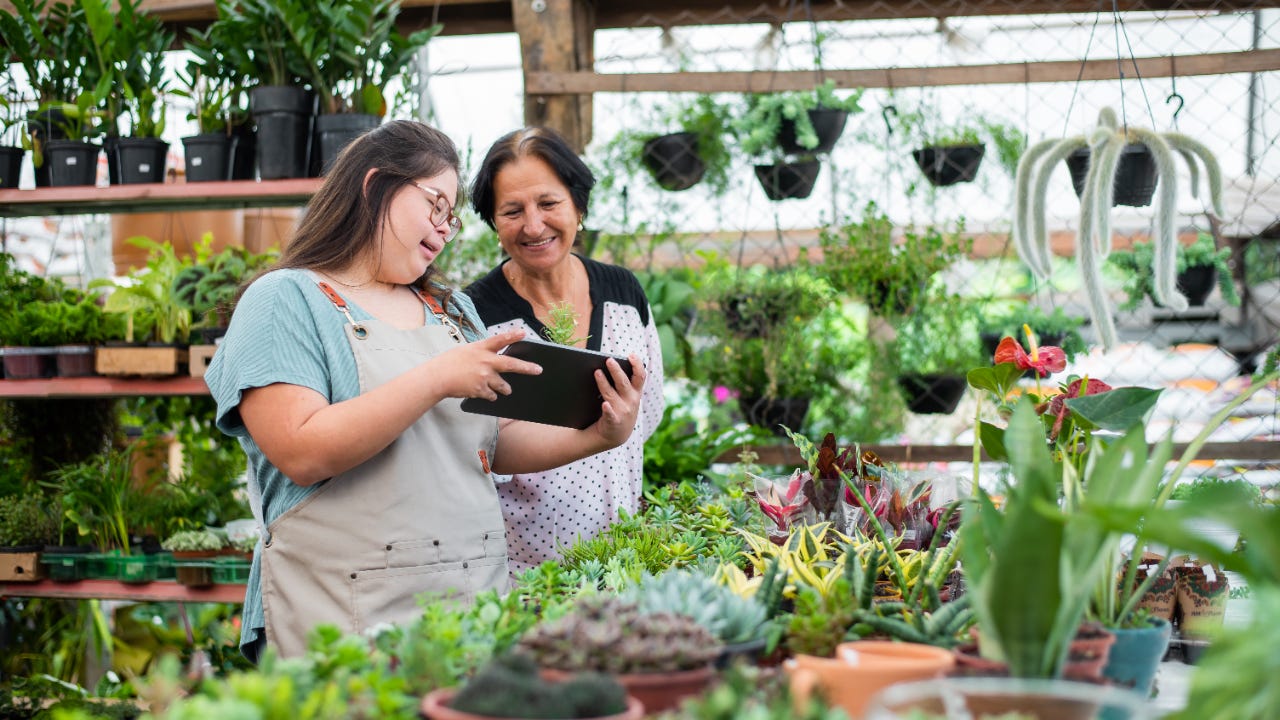 Two women in a plant business reviewing a tablet.